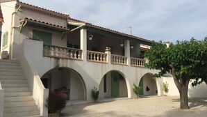 A building with a covered patio, multiple arches, and a staircase leading to an upper level. - Sur les pas de Pagnol (Aubagne)