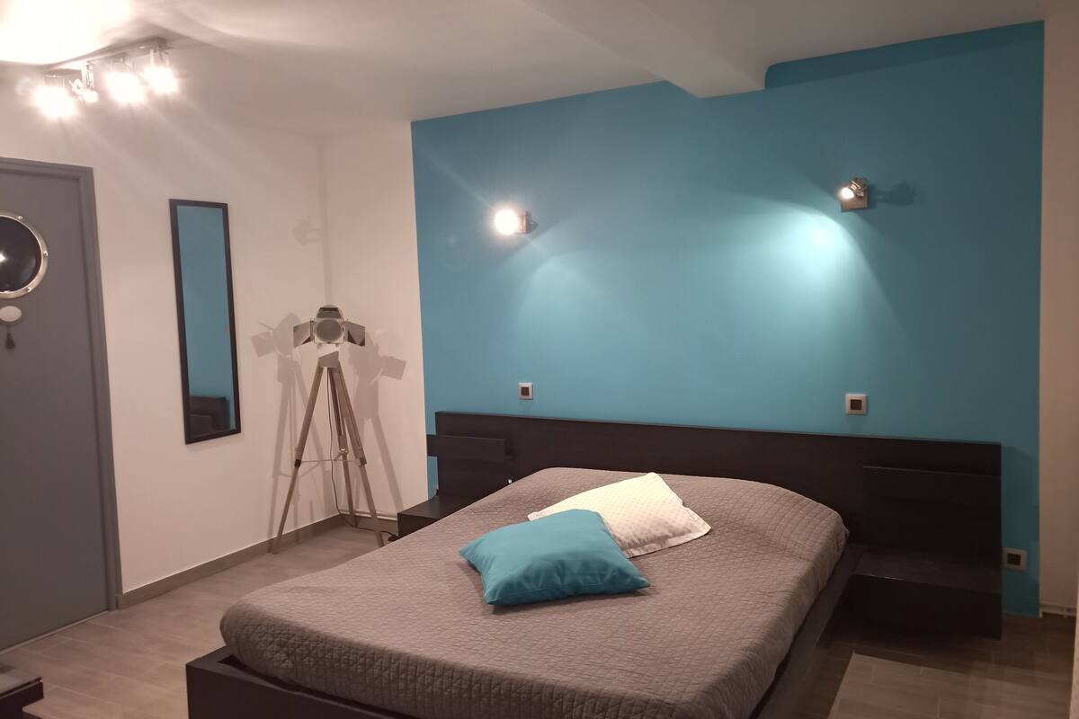 Un dormitorio con una cama, un trípode y un espejo en la pared.