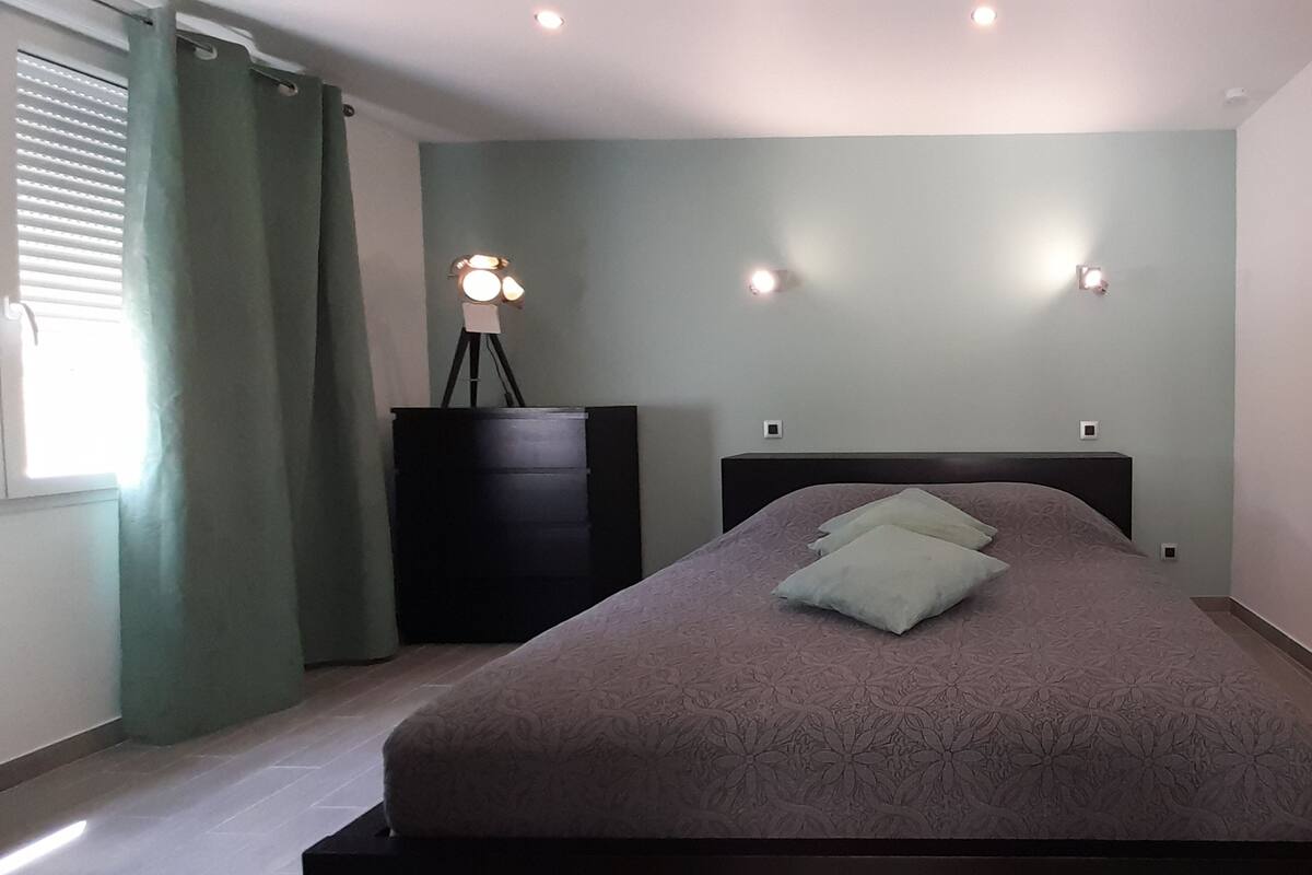 Un dormitorio con cama, cómoda, lámpara y ventana con cortinas.