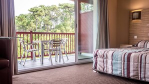 A hotel room with a balcony, a bed, and a table with chairs.