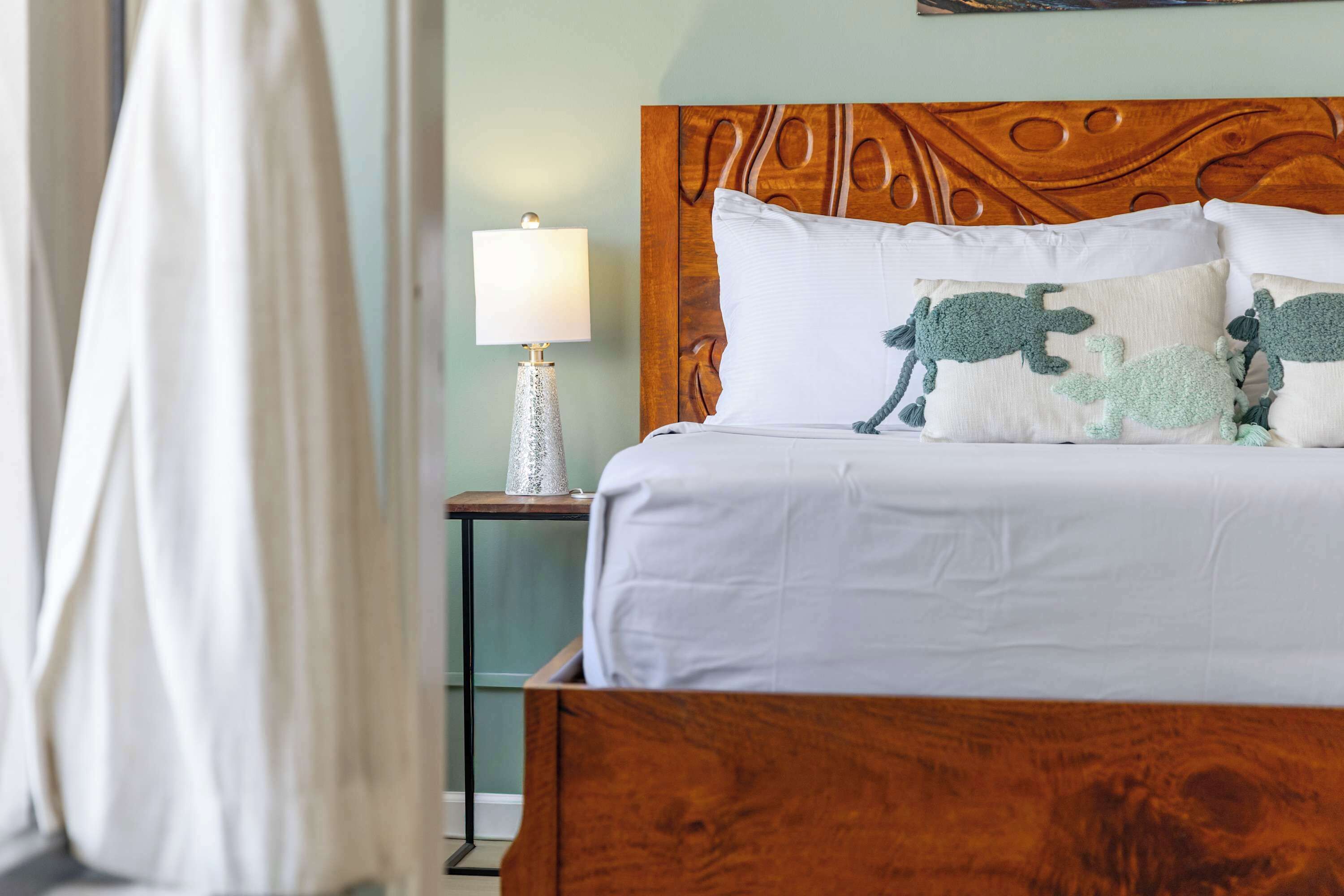 A bed with a wooden headboard, a bedside lamp, and decorative pillows.