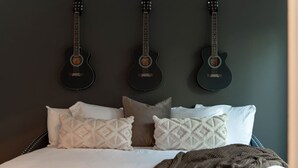 A bedroom with a bed, pillows, and three guitars mounted on the wall. - Music City Command Center: 3BR Berry Hill Home (Berry Hill)
