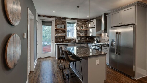 A modern kitchen with a central island, stainless steel appliances, and a brick backsplash. - Music City Command Center: 3BR Berry Hill Home (Berry Hill)