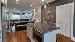 A modern kitchen with granite countertops, a built-in oven, and a dining area with a pool table. - Music City Command Center: 3BR Berry Hill Home (Berry Hill)