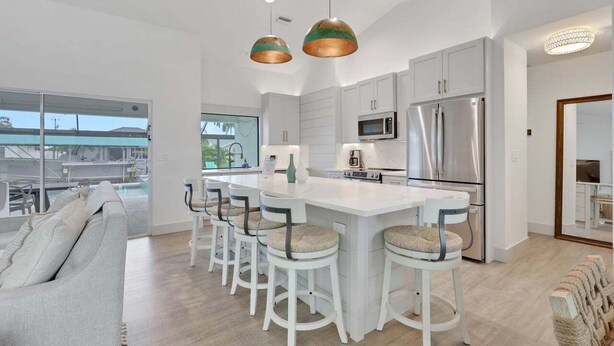 A modern kitchen with white cabinetry, stainless steel appliances, and a central island with bar stools.