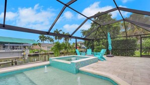 A covered outdoor swimming pool with a view of a lake and palm trees.