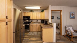 Una cocina con armarios de madera, un refrigerador, un microondas y una cafetera.