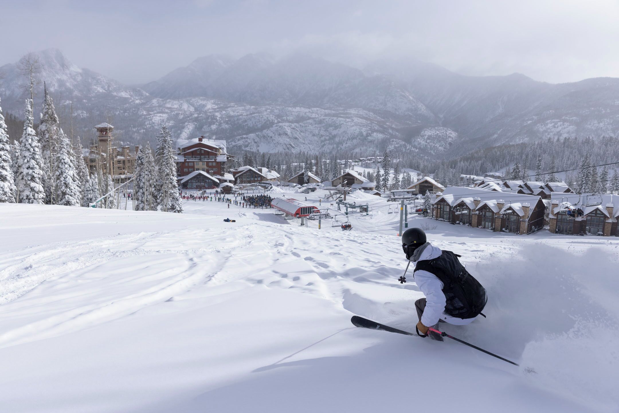 Un centro de esquí con edificios cubiertos de nieve y una pista de esquí.
