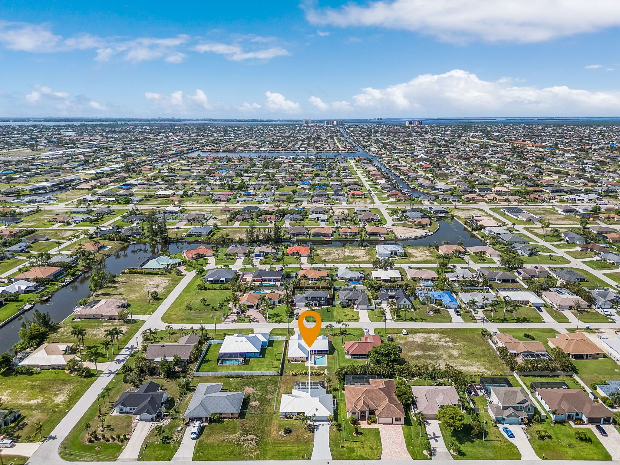 An aerial view of a residential area with houses, roads, and a canal.