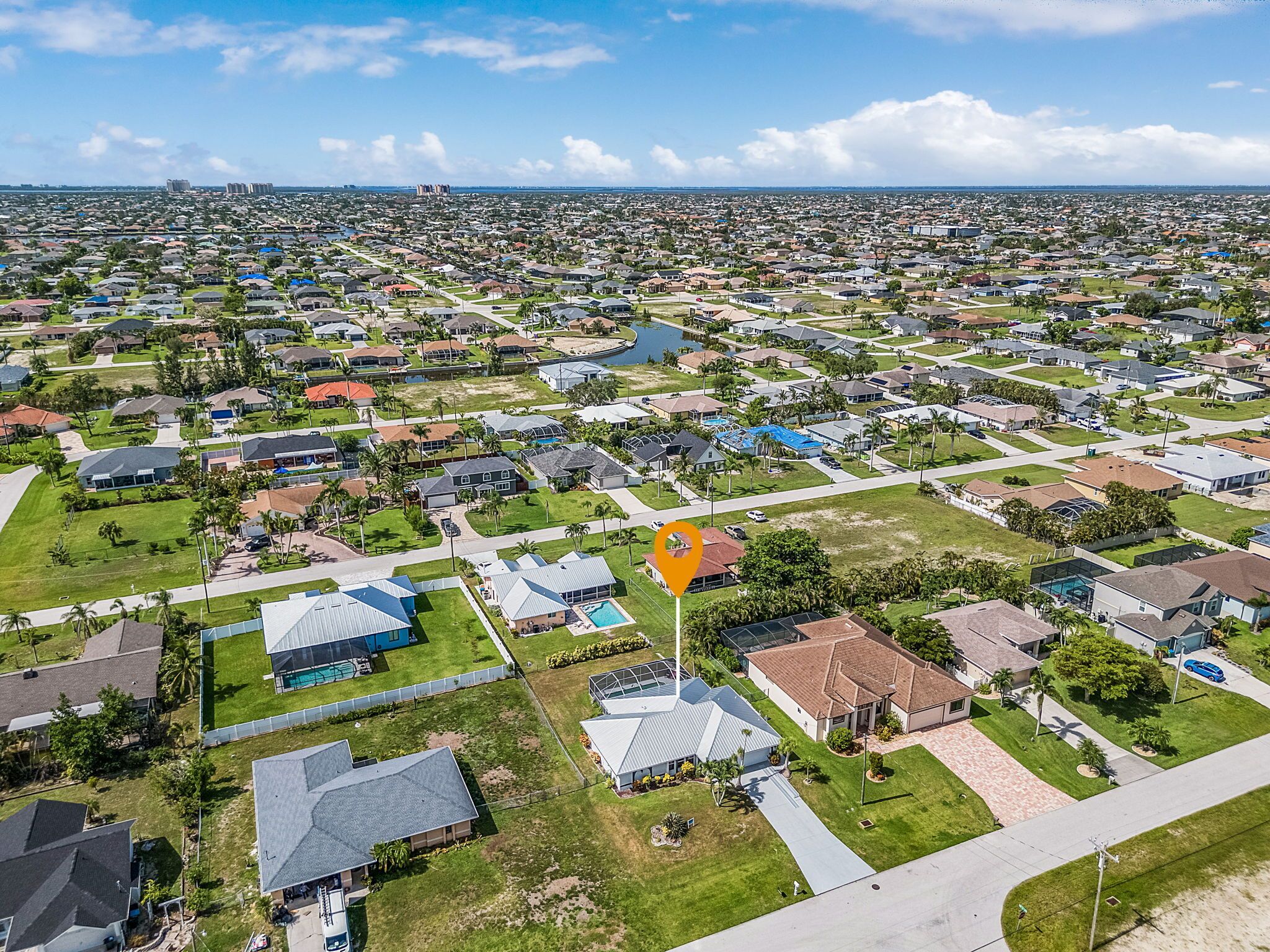 Vista aerea di una zona residenziale con case, aree verdi e una piscina.
