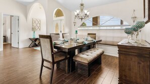 A dining area with a wooden table set for four, a bench, and a chandelier. - Pool home on a serene canal, Quiet area for relaxation.- Villa Del Mar - Roelens Vacations (Cape Coral)