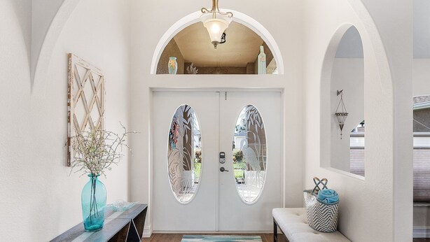 A foyer with a double door, a bench, a small table with a vase, and a hanging light fixture. - Pool home on a serene canal, Quiet area for relaxation.- Villa Del Mar - Roelens Vacations (Cape Coral)