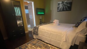 Un dormitorio con cama, televisión, puerta y alfombra.