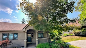 A two-story house with a front porch, a driveway, and a landscaped garden. - FV44 tastefully updated single level with AC, WiFi, minutes from skiing, Dog Friendly! (Bretton Woods)