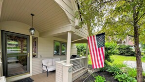 A covered porch with a seating area, a grill, and an American flag. - FV44 tastefully updated single level with AC, WiFi, minutes from skiing, Dog Friendly! (Bretton Woods)