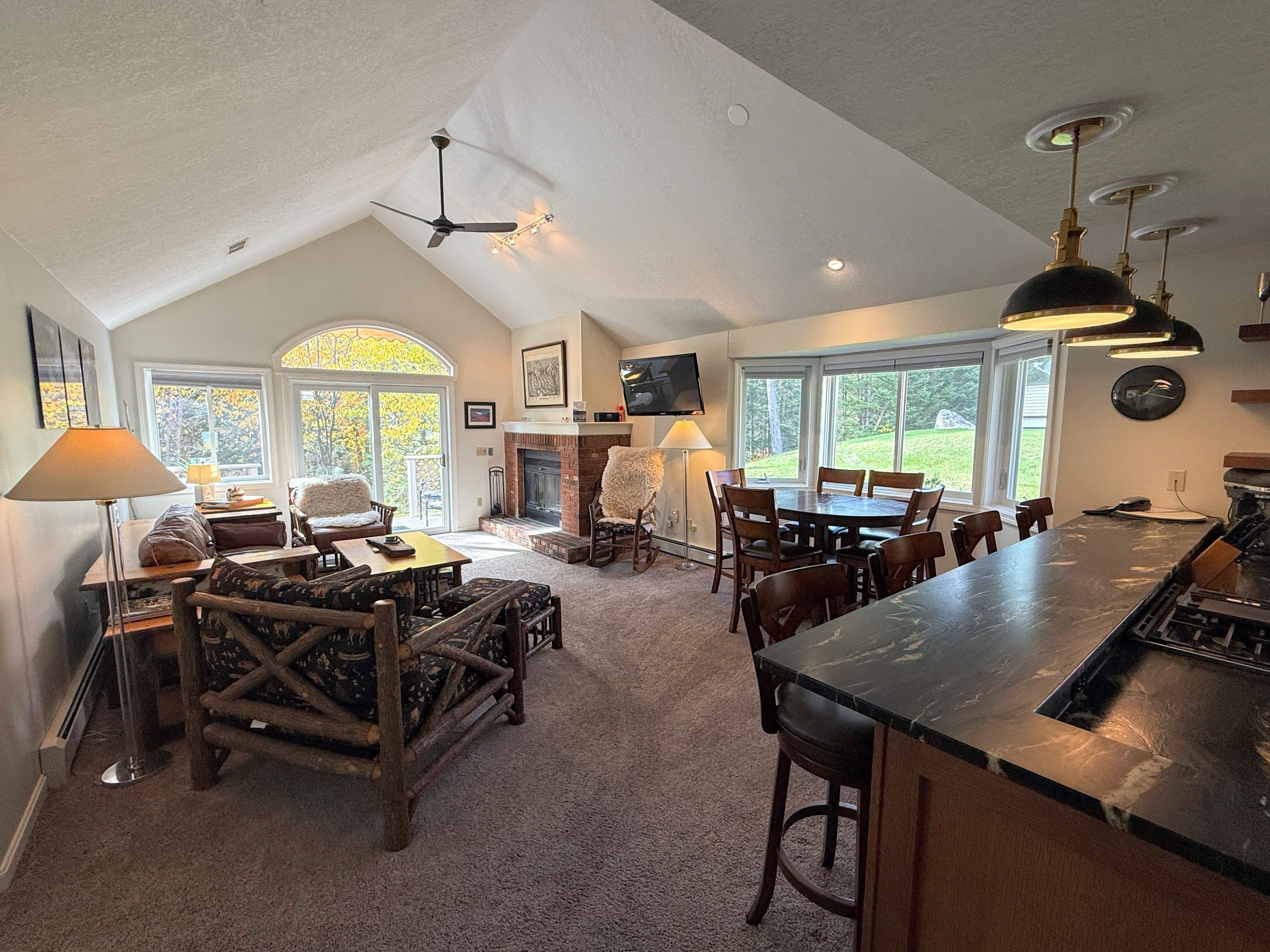 A spacious living area with a fireplace, a dining table, and a kitchen with a bar.