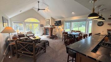 A spacious living area with a fireplace, a dining table, and a kitchen with a bar.