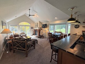 A spacious living area with a fireplace, a dining table, and a kitchen with a bar.