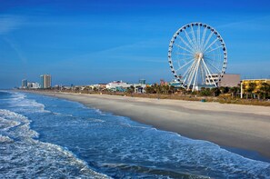 A beach with a large Ferris wheel in the background.