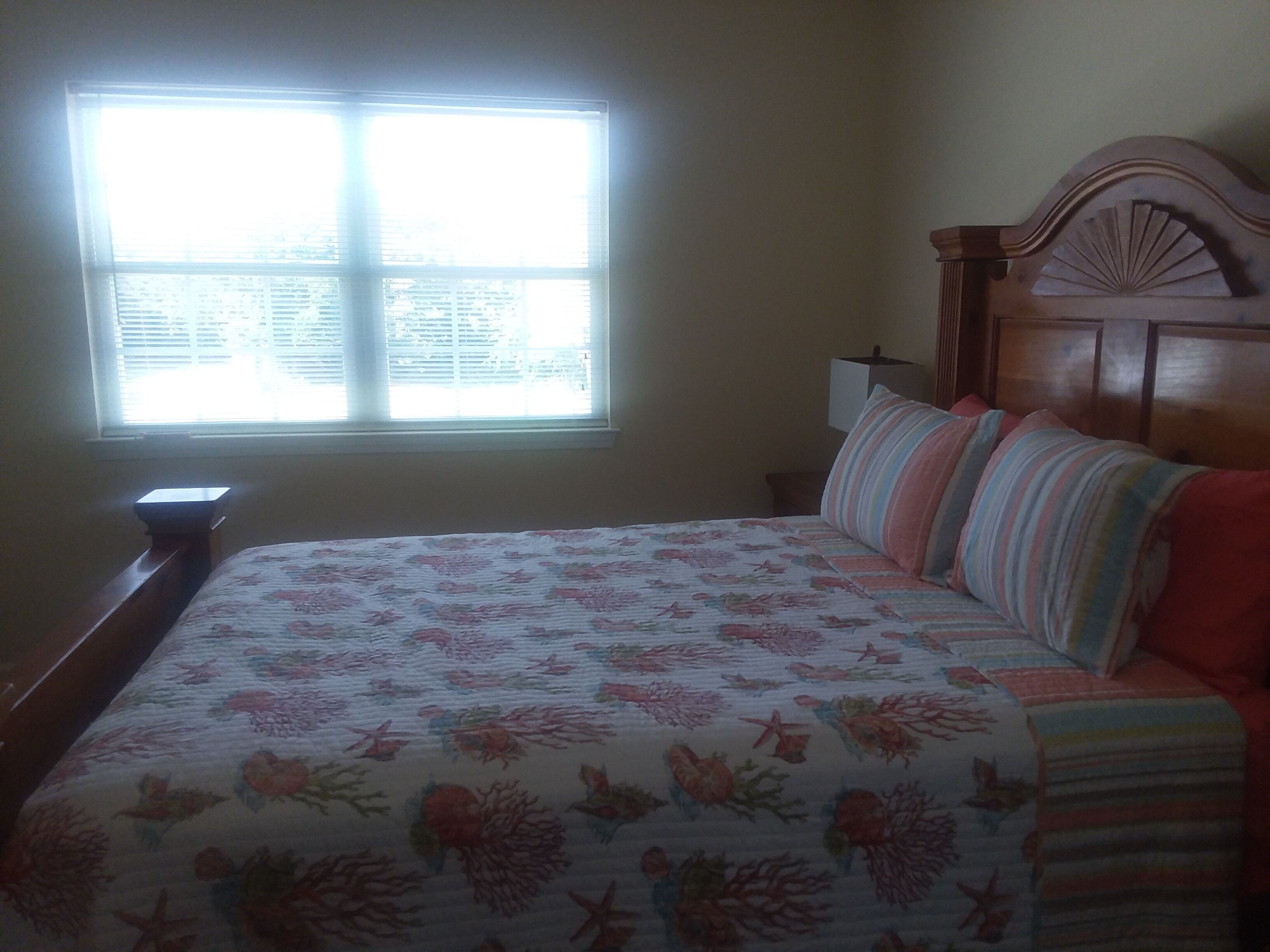 A bedroom with a bed, a window, and a nightstand.