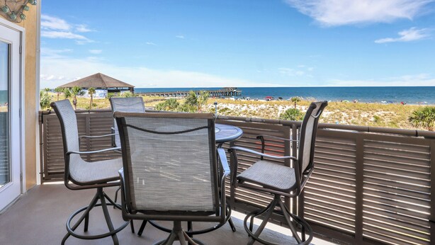 Varanda com vista para a praia, com mesa e cadeiras.