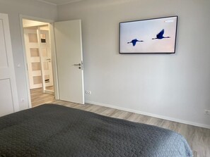 Makuuhuone, jossa on sänky, ovi, joka johtaa käytävään, ja seinälle ripustettu lintukuva.