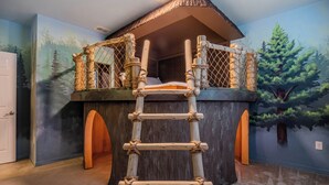 A playhouse with a ladder leading to a rope ladder entrance, surrounded by forest-themed wall murals. - Waterpark, Arcades, Pool Table, Drive-in Theater, Poker Table: Treasured Days (Davenport)