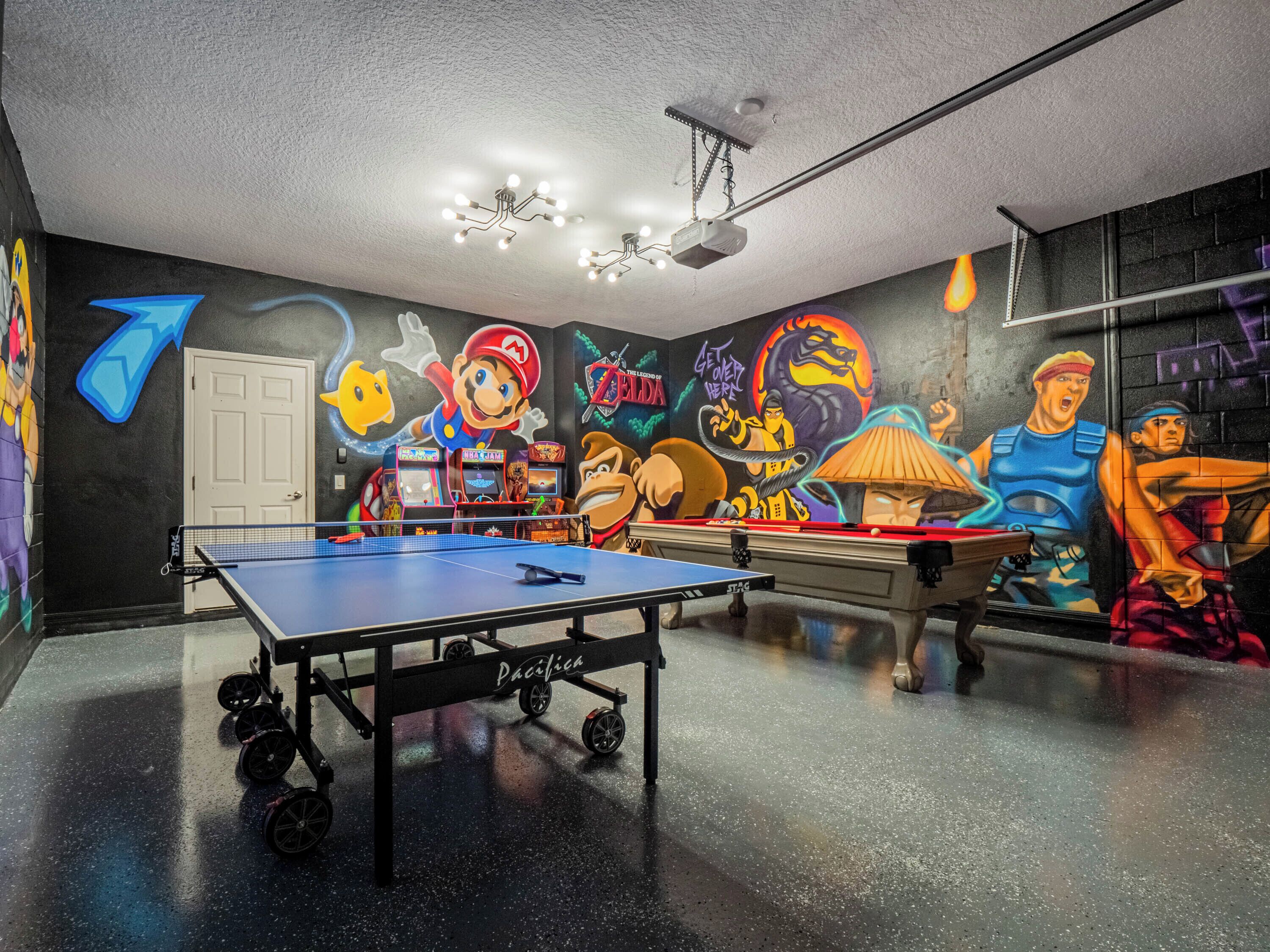 Ein Zimmer mit Tischtennisplatte, Spielautomaten und farbenfrohen Graffiti.