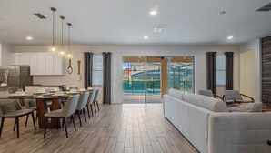 A modern kitchen with white cabinets, a dining area with a table and chairs, and a living room with a sofa and armchairs. - Waterpark, Arcades, Pool Table, Drive-in Theater, Poker Table: Treasured Days (Davenport)