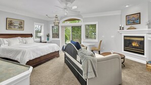 Une chambre à coucher avec un lit, une chaise, une cheminée et une vue sur l’extérieur.