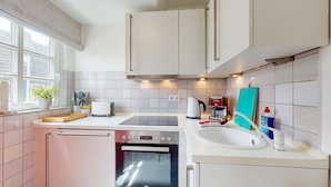 Een moderne keuken met witte kasten, een ingebouwde oven, een spoelbak en een raam met uitzicht.