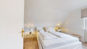 Een slaapkamer met een bed, nachtkastjes, een lamp en een raam.
