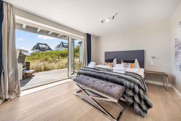 Une chambre à coucher avec un lit, un banc, une table de chevet et une vue sur l’extérieur.