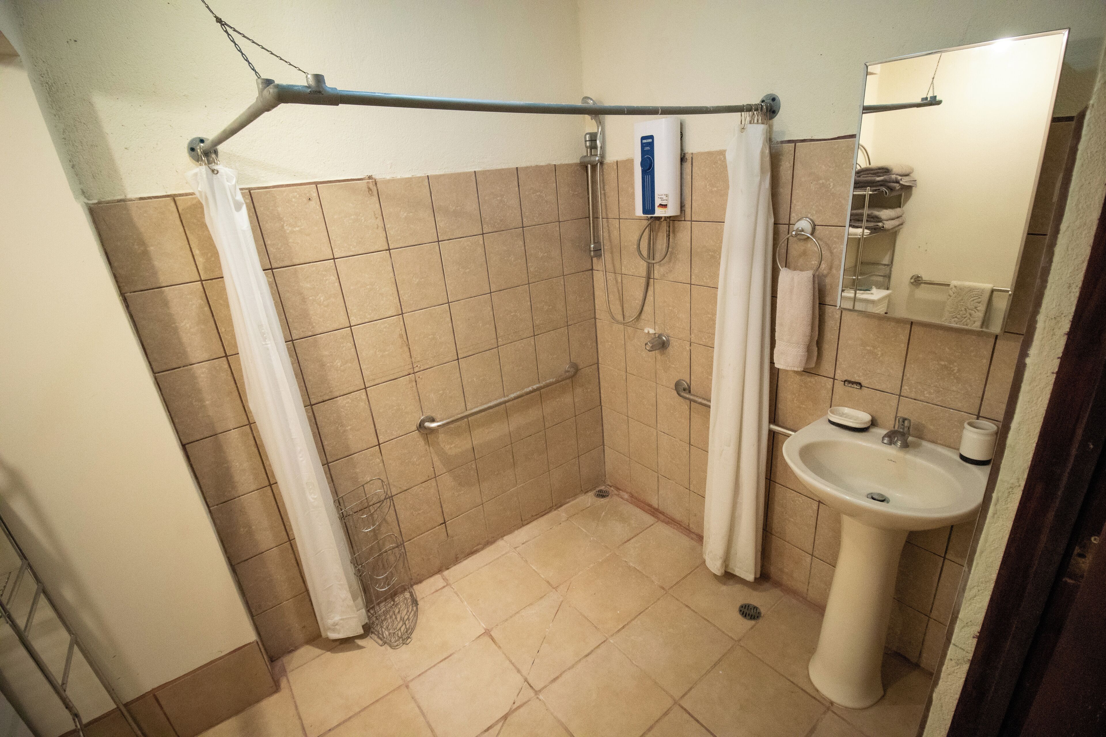 A small bathroom with a shower, grab bar, and sink.