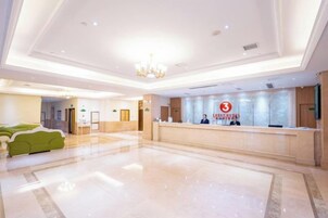Vestíbulo de hotel con recepción, zona de estar y candelabro.
