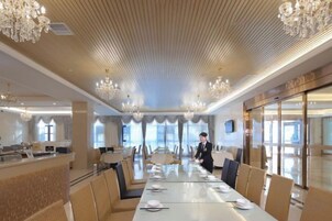 Un comedor amplio con mesas largas, candelabros y vistas al exterior.