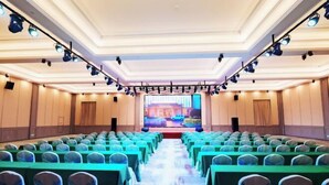 A conference room with rows of tables and chairs, a large screen at the front, and ceiling lights. - Vienna 3 Best Hotel (Changsha Wangcheng Economic Development Zone) (Changsha)