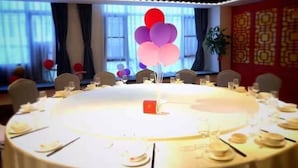 A round table set for a meal with a red centerpiece, surrounded by chairs and dining tables. - Vienna 3 Best Hotel (Changsha Wangcheng Economic Development Zone) (Changsha)
