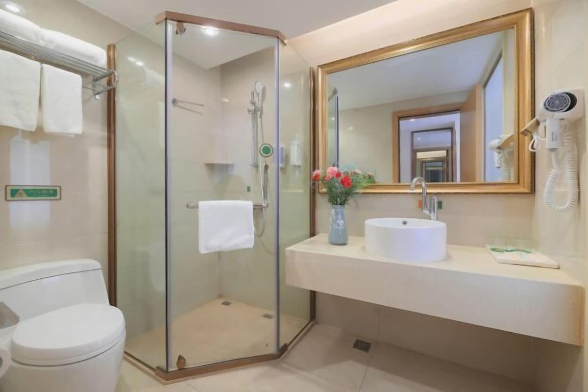 Een badkamer met een douchecabine van glas, een wastafel met spiegel en een toilet.