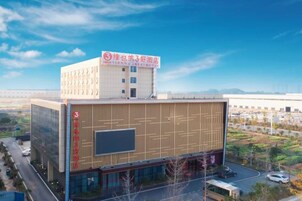 Un edificio moderno con un letrero llamativo en la parte superior, grandes ventanales en la fachada y un estacionamiento al frente.