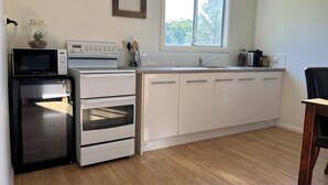 Une cuisine équipée d’un four à micro-ondes, d’une cuisinière, d’un four et d’une fenêtre située au-dessus de l’évier.