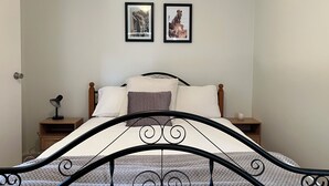Une chambre à coucher avec un lit, deux tables de chevet, une lampe et deux tableaux encadrés accrochés au mur.