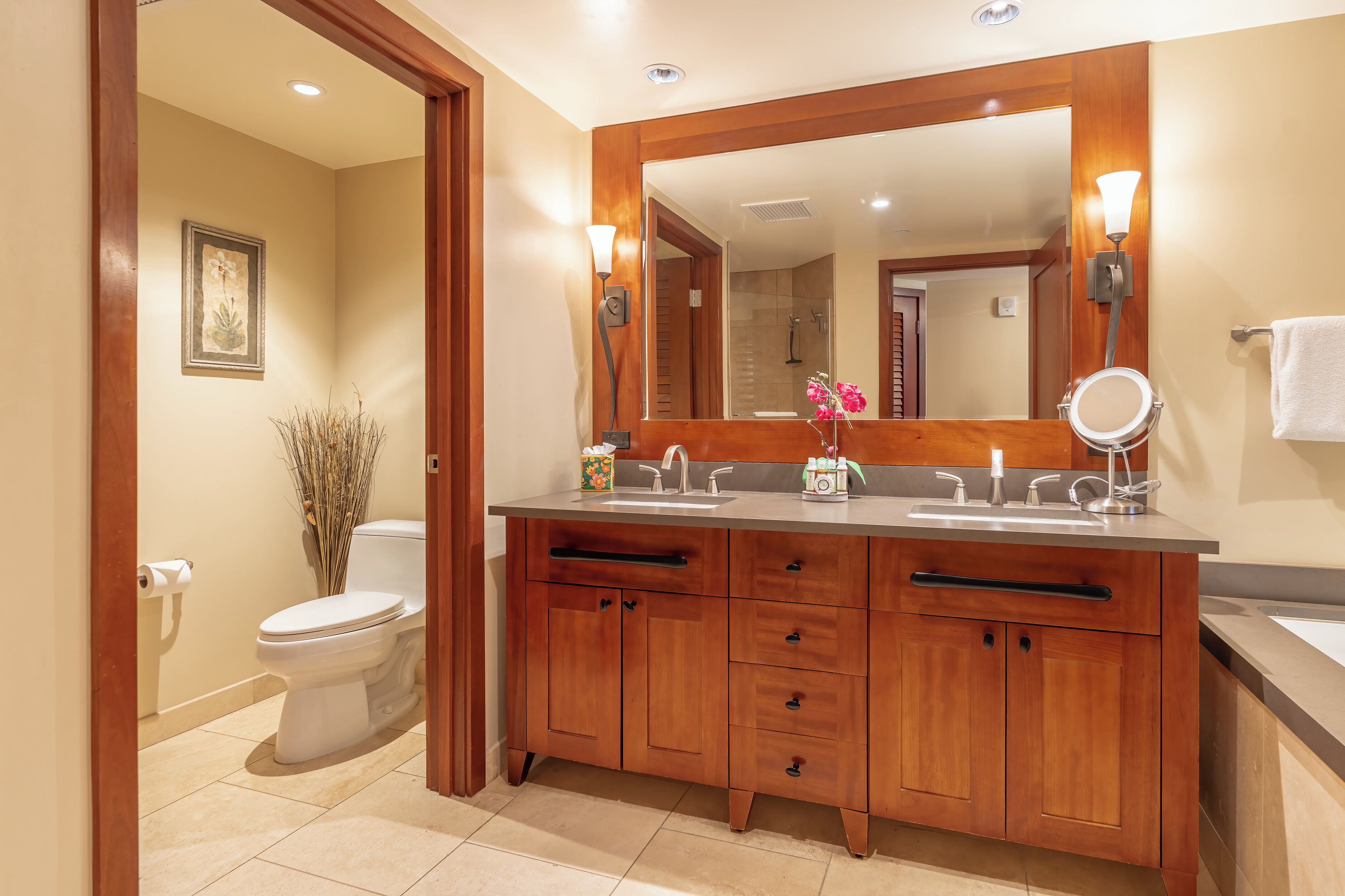 Une salle de bain avec un meuble-lavabo en bois, un grand miroir, des toilettes et un lavabo.
