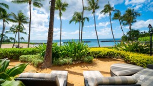Une plage avec des palmiers, des chaises longues et un ciel dégagé.