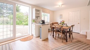 A modern kitchen with a dining area, large windows, and a view of greenery outside. - Harbour View, Walberswick (Walberswick)