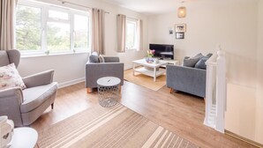 A modern living room with a sofa, armchairs, a coffee table, and a TV. - Harbour View, Walberswick (Walberswick)