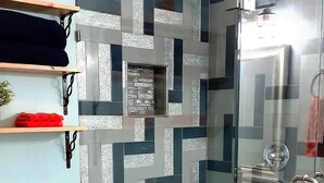 Une salle de bain moderne dotée d’une douche à parois de verre, de toilettes et d’un lavabo avec un pare-éclaboussures en verre.