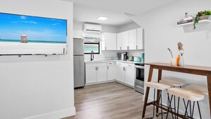 Een moderne keuken met witte kasten, een houten aanrecht en een bar met krukken.