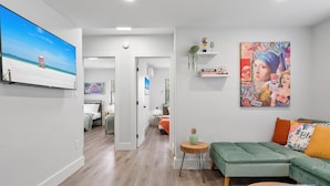 Een moderne woonkamer met een groene bank, een salontafel en een schilderij van een stadsgezicht.