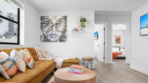 Een moderne woonkamer met een bank, een ronde salontafel en een groot abstract schilderij aan de muur.